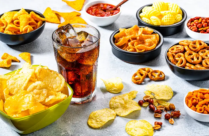 cola soda glass and salty snacks shot on gray table